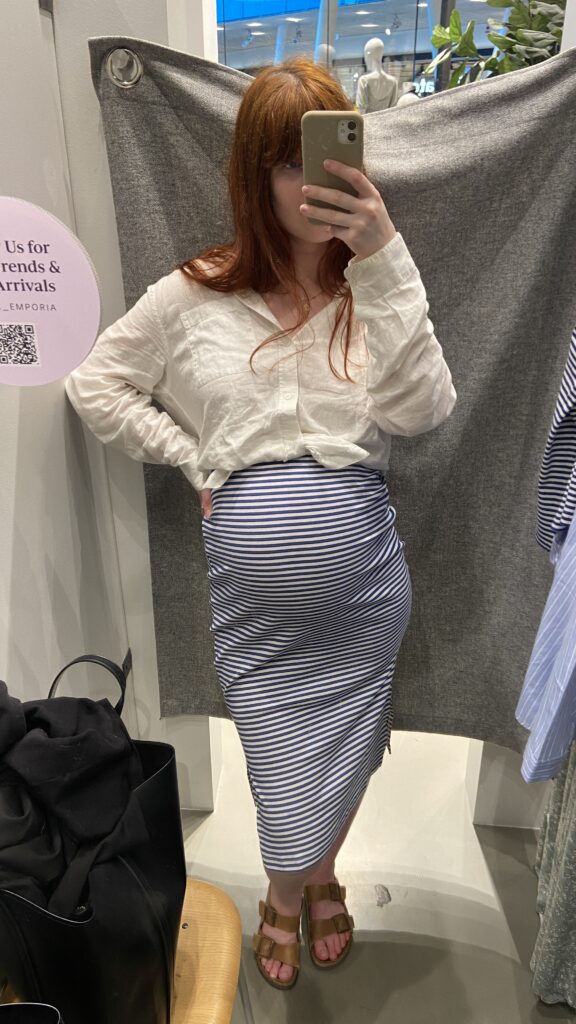 the new mom trying on a blue and white striped skirt. 